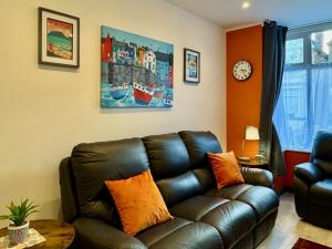 a living room with a leather couch and a clock at Crow Hill House - Tranquil Escape Hideaway in Cleethorpes
