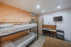 a room with two bunk beds and a desk at Окремі номери поруч з Південним вокзалом in Kharkiv