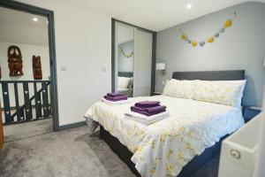 a bedroom with a bed with purple towels on it at Amazing coastal & sunset views in Eryri (Snowdonia) in Llanllyfni