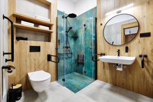 a bathroom with a shower and a sink and a mirror at Resort Zacisze Apartamenty in Konopnica