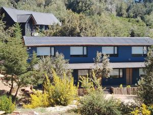 ein blaues Haus mit Bäumen davor in der Unterkunft SUOMI in Villa Pehuenia