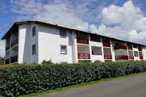 un bâtiment blanc avec des fenêtres rouges et une rue dans l'établissement Studio Ttikia, à Cambo-les-Bains