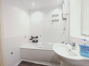 a white bathroom with a sink and a bath tub at Barking 1 bed flat With Parking in Barking