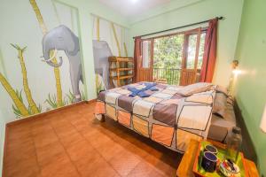 a bedroom with a bed and a mural of an elephant at Chrissie's Hotel in Thekkady