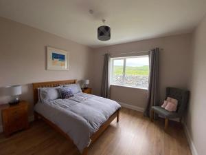 a bedroom with a bed and a window and a chair at Inis Mor, Aran Islands Luxury 5 bedroom with Seaviews 