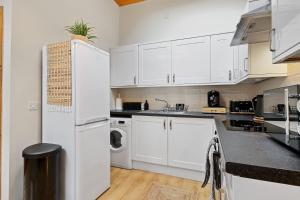 a kitchen with white cabinets and a white refrigerator at The Hoxton Loft - Top Floor Shoreditch Apartment in London