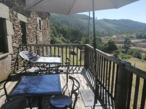 a balcony with tables and chairs and an umbrella at Casa de Campo "Quinta do Cadafaz" in Alvarenga