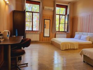 a bedroom with a bed and a desk and windows at Roger's Hotel in Ruse