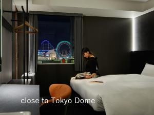 une femme dans une chambre d'hôtel à la recherche d'un livre dans l'établissement sequence SUIDOBASHI - Tokyo, à Tokyo