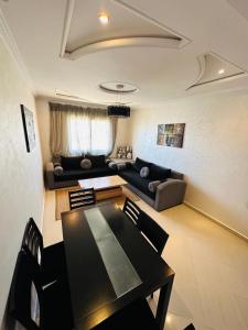 ein Wohnzimmer mit einem Tisch und einem Sofa in der Unterkunft appartement de vacances achakar avec plage&piscine in Tangier