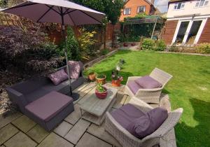 eine Terrasse mit Stühlen und einem Sonnenschirm im Hof in der Unterkunft Rose Garden Retreat in Rayleigh