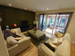 a living room with two couches and a table at Rose Garden Retreat in Rayleigh