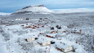 a village covered in snow with a mountain in the background at Aurora Apartment Kilpisjärvi in Kilpisjärvi