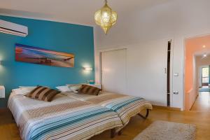 1 dormitorio con 1 cama grande y pared azul en Agradable casa con entrada propia a la playa, en Playa del Águila