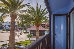 balcón con palmeras y vistas a la piscina en Agradable casa con entrada propia a la playa, en Playa del Águila