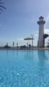 a pool of water with a lighthouse in the background at Agradable casa con entrada propia a la playa in Playa del Aguila