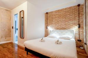 a bedroom with a large white bed with a brick wall at NOUVEAU - Loft industriel - 4pp in Paris