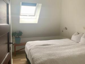 a bedroom with a white bed and a window at Zolder appartement Le Grenier in Dilsen-Stokkem