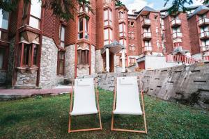 Deux chaises pliantes assises dans l'herbe devant un bâtiment dans l'établissement THE NEST Alpine Loft Ski-in Ski-out, à Breuil-Cervinia
