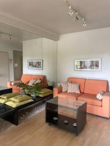 a living room with two orange couches and a table at Depto Cómodo, amplio y funcional ,a pasos de Blvd. in Vuelta del Paraguayo