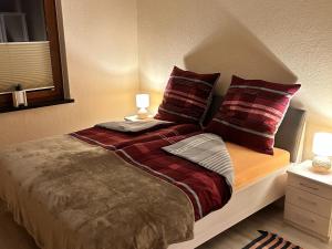łóżko z czerwonymi i brązowymi poduszkami w obiekcie Beautiful holiday apartment in Stolpe w mieście Stolpen