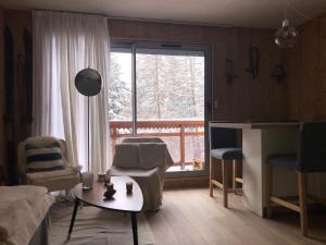 a living room with a couch and a table and a window at Appartement 6 personnes aux 2 Alpes, au pied des pistes - Wi-fi, Parking gratuit, Terrasse vue sur jardin in Les Deux Alpes