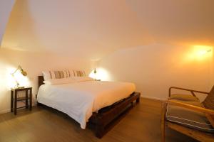 um quarto com uma grande cama branca e uma cadeira em Old Stone House em Bari