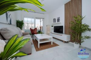 sala de estar con sofá y TV y algunas plantas en Breakfast at Tiffanys en La Herradura