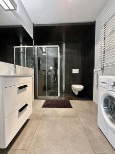 a bathroom with a shower and a washing machine at LuxApart Kalisz in Kalisz