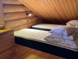 two beds in a room with a wooden ceiling at Ruska 2, Ylläs - Hirsimökki järvi- ja tunturimaisemilla in Äkäslompolo