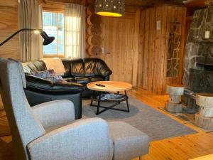 a living room with a leather couch and a table at Ruska 2, Ylläs - Hirsimökki järvi- ja tunturimaisemilla in Äkäslompolo