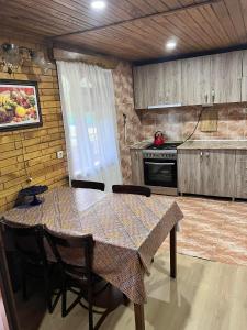 La cocina está equipada con mesa, sillas, mesa y fogones. en Villa Kursebi, en Kutaisi