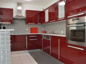une cuisine équipée de placards rouges et d'appareils en acier inoxydable dans l'établissement Appartement Argelès-sur-Mer, 3 pièces, 4 personnes - FR-1-225-652, à Argelès-sur-Mer