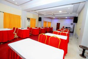 una sala de conferencias con mesas y sillas rojas y blancas en Benin Metropole Hotel, en Parakou