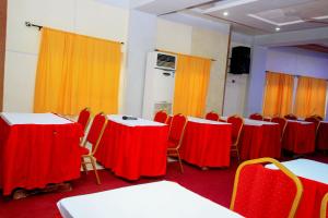 Zimmer mit Tischen und Stühlen sowie roten und gelben Vorhängen in der Unterkunft Benin Metropole Hotel in Parakou