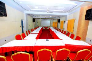 una gran sala de conferencias con una mesa larga y sillas rojas en Benin Metropole Hotel, en Parakou