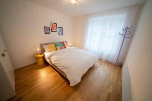1 dormitorio con cama blanca y ventana en theCorner 2-Bedroom Apartment, en Schwändi
