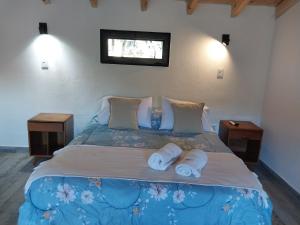 1 dormitorio con 1 cama grande y toallas. en SUOMI en Villa Pehuenia