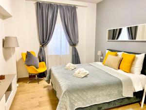 a bedroom with a bed and a yellow chair at D&A City Center Apartments with free parking in Pula