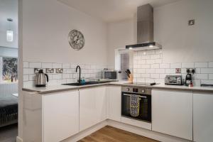 uma cozinha com armários brancos e um forno com placa de fogão em Coppergate Mews Apartment Doncaster 3 em Doncaster
