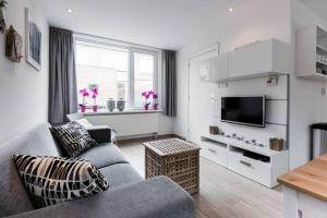 a living room with a couch and a tv at Modern Ingericht Vakantiehuis - Rust & Strand op 350m in Egmond aan Zee