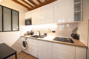 een keuken met witte kasten en een wastafel bij Appartement cosy Montorgueil (Bonne Nouvelle) in Parijs
