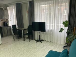 een woonkamer met een televisie en een tafel met stoelen bij Apartment Artynova 29 in Vinnytsya