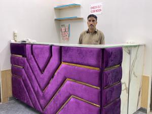 un hombre parado detrás de un objeto púrpura en Eden Plus Executive Hotel en Lahore