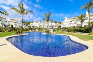 a large swimming pool in a resort with palm trees at Los Monteros Palm Beach - sea & pool view in Marbella