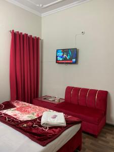 a bedroom with a red bed and a couch at Eden Plus Executive Hotel in Lahore