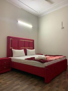 a bedroom with a large bed with a red headboard at Eden Plus Executive Hotel in Lahore