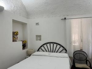 Villa Manni في بروسيدا: غرفة نوم بيضاء بها سرير ونافذة