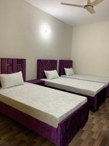 two beds in a room with purple furniture at Eden Plus Executive Hotel in Lahore