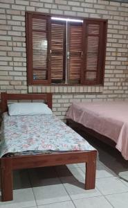 a bedroom with two beds and windows with shutters at Sobrado praia cachoeira in Florianópolis